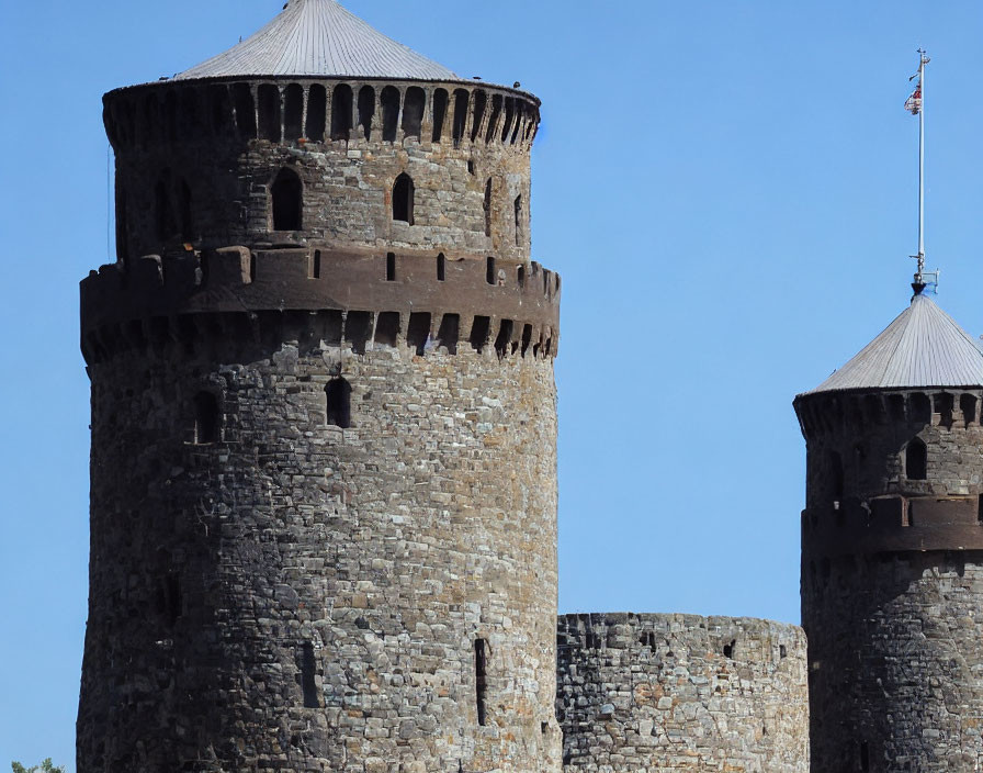 Medieval stone towers with conical roofs under clear blue sky