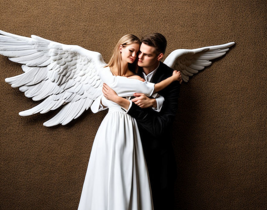 Formal wear couple embracing with angel wings on brown backdrop