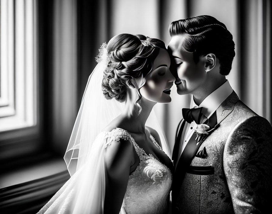 Monochrome photo of bride and groom in elegant attire sharing intimate moment