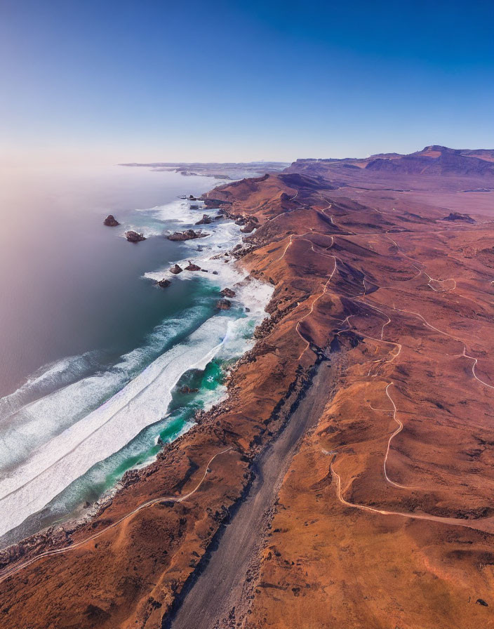 Rugged coastline with reddish-brown cliffs and winding road