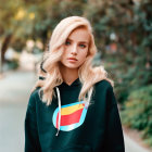 Blonde Woman in Colorful Logo Hoodie on Green Pathway