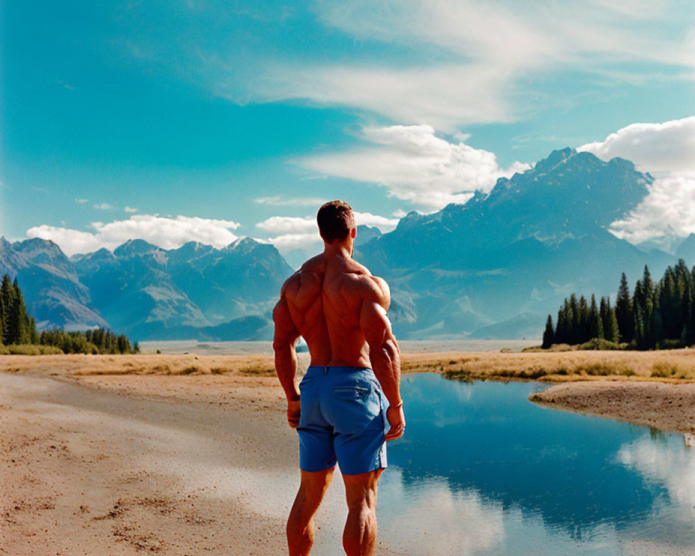 Muscular Person in Blue Shorts by Lake and Mountains