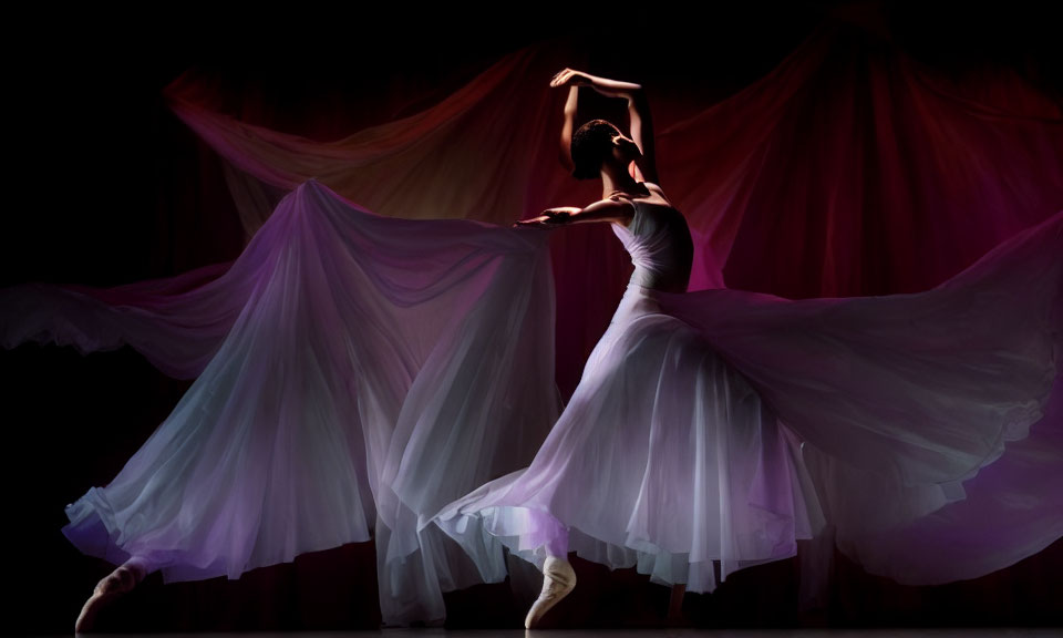 Ballet dancer in white tutu with swirling purple and pink fabric on dark background