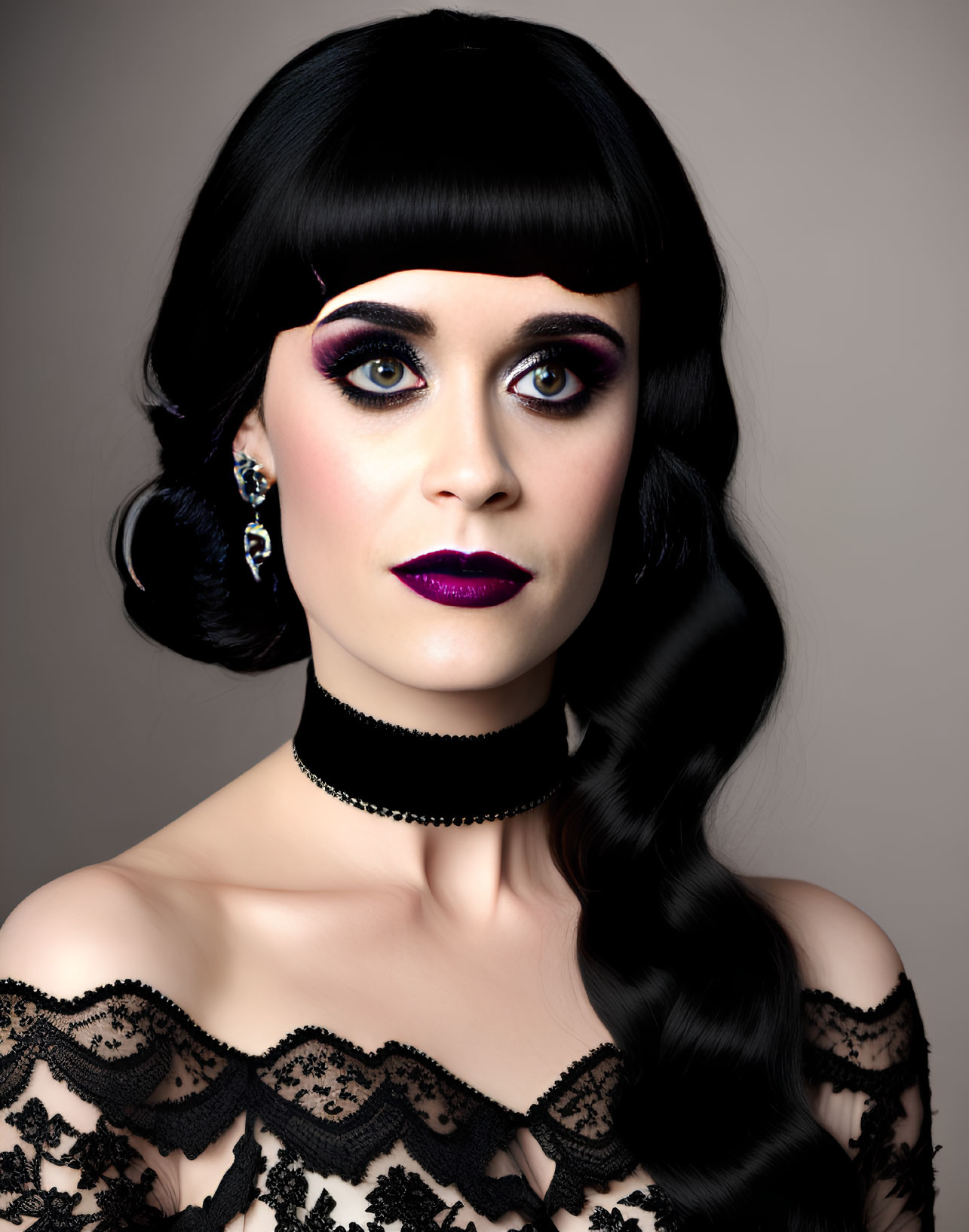 Dark-haired woman in dramatic makeup and lace dress on gray background