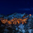 Snowy mountain village at night with starlit sky