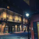 Vintage street at night with ornate buildings, classic cars, and starry sky.