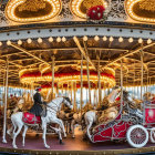 Ornate carousel with golden embellishments and white horses at dusk