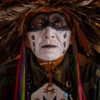 Native American in Traditional Attire with Feather Headdress and Face Paint