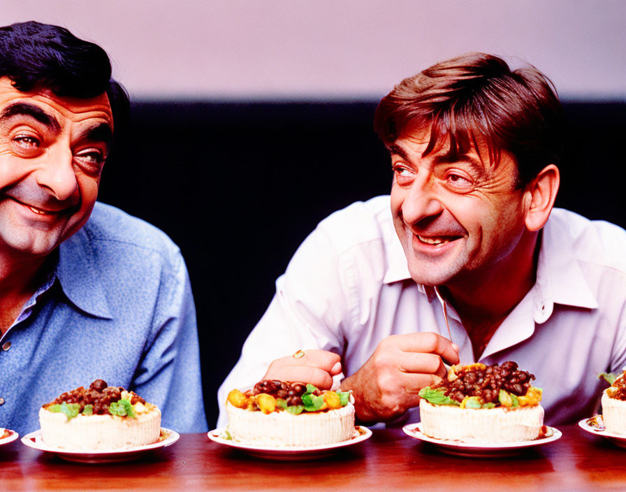 Identical Men Smiling at Food Plates on Table