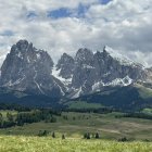 Snow-covered rocky peaks and serene valley landscape with winding rivers and sparse trees.