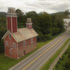 Vintage-style red firehouse with watchtower in serene natural setting