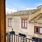 Charming village house with orange flowers, blue shutters, and red door on balcony with wrought-