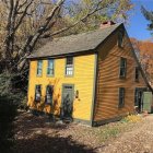 Impressionistic painting: Yellow house, blue roof, garden, trees