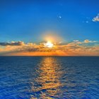 Scenic sunrise over wavy ocean with bright sun and celestial bodies