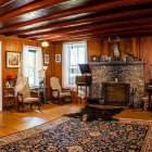 Luxurious Wooden Interior with Green Seating, Fireplace, Persian Rug, Windows, and Houseplants