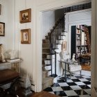 Luxurious interior with grand staircase, white balustrades, blue walls, checkered floor, framed