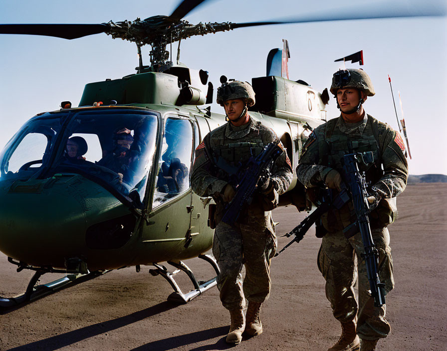 Camouflaged soldiers by military helicopter.