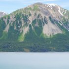 Tranquil waters and misty landscape with lush greenery and towering mountains