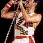 Energetic performer in white tank top and pants singing with red armband