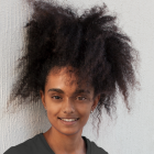 Smiling young girl with curly black hair and purple highlights