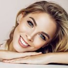 Smiling woman portrait with blue eyes and blond hair on light background