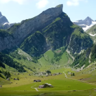 Scenic landscape painting with green hills, cabins, and mountains