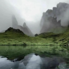 Sailboats on choppy waters with forested hill and cloudy sky