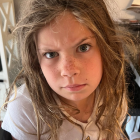 Young girl with curly hair and striking eyes in sunlight wearing polka-dot hoodie