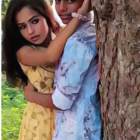 Animated couple embraces beside a tree in yellow and blue attire amid lush greenery