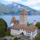 White house with red roof and tower by vibrant blue waters and green hills