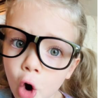 Young Child with Curly Hair in Oversized Black Glasses and Puckered Lips