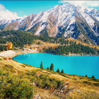 Colorful lakeside village painting with mountains, trees, and clear blue sky