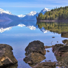 Tranquil lake with snow-capped mountains, autumn forest, and clear blue sky