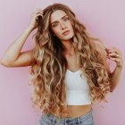 Woman with ornate peacock feather hair and citrus slices on pink background