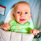 Baby with Blue Eyes in Green Shirt on Abstract Background