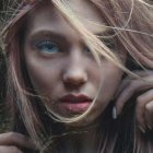 Close-Up of Woman with Striking Blue Eyes and Tousled Hair in Mystical Light Swirl