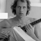 Monochrome image: Curly-haired man playing guitar pensively