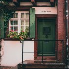 Green door, window shutters, ivy wall, pink roses, street lamp in a quaint entrance