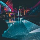 Neon-lit tropical beach at night with aurora borealis sky