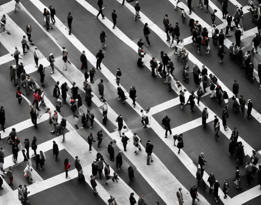 Busy pedestrian crossing with people on zebra stripes, selective red color highlight