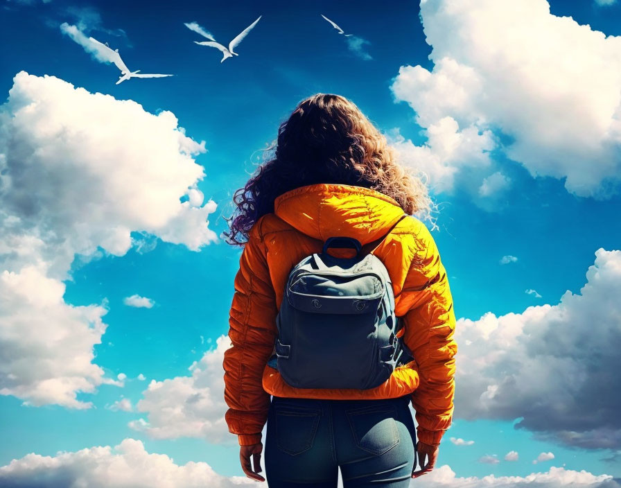 Person in Orange Jacket Stands Under Blue Sky