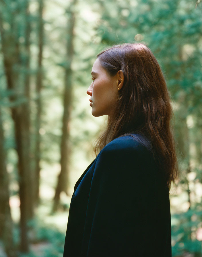 Woman with Long Hair in Forest, Sunlight Filtering, Wearing Dark Coat