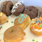 Assorted colorful donuts with frosting and sprinkles on white plate