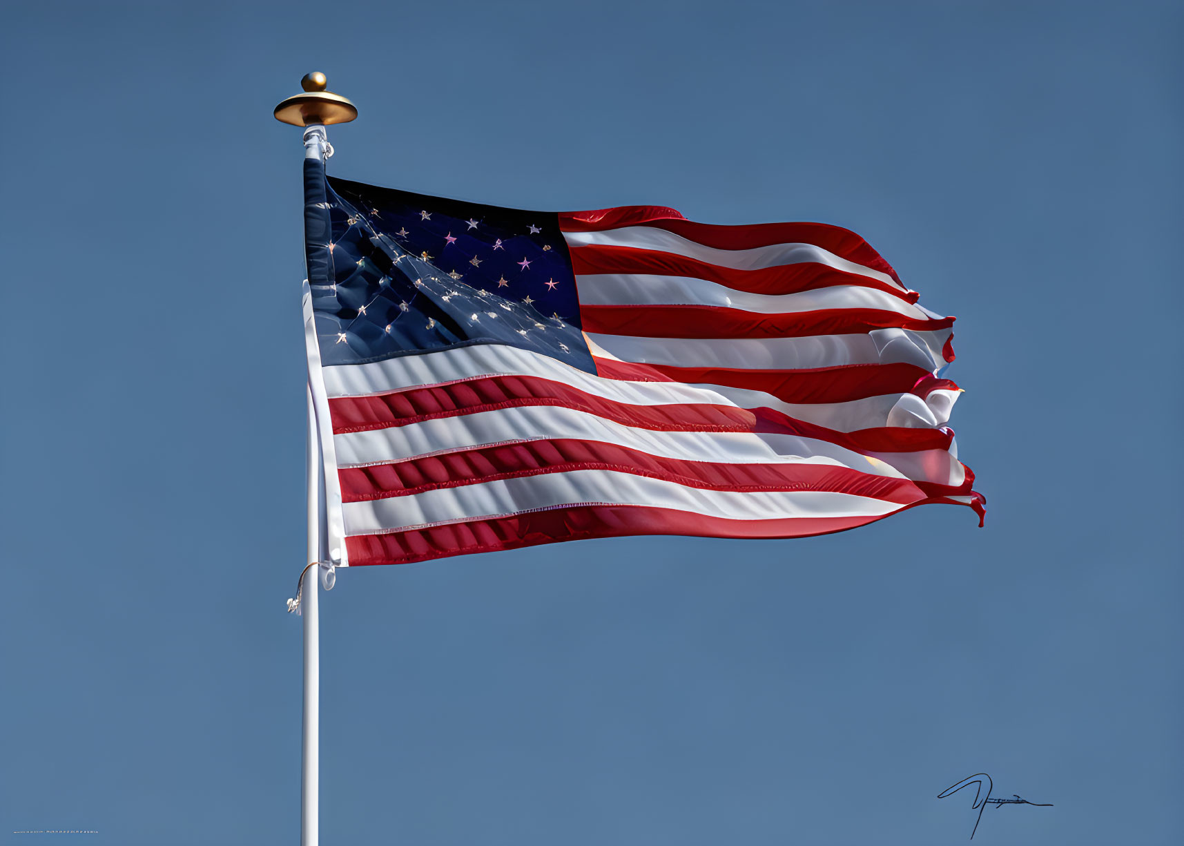 American flag waving on white pole under clear blue sky