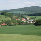 Scenic village nestled in rolling green hills with mountain backdrop