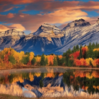 Colorful Autumn Trees Reflecting in Tranquil Lake with Snow-Capped Mountains and Vibrant Sky