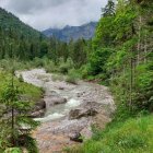 Scenic landscape with river, flowers, trees, mountains & sky