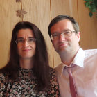 Man and woman in vintage attire with hats and glasses in autumn leaf setting