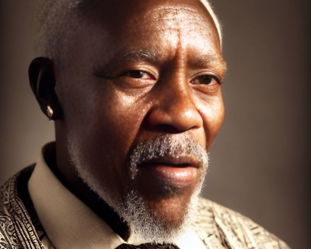 Elderly man with grey beard in patterned shirt and tie