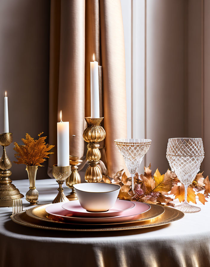 Sophisticated table setting with gold accents, crystal glasses, candles, and autumn leaves on draped curtain